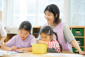 学童で職員が子どもたちの美術活動を支援している様子